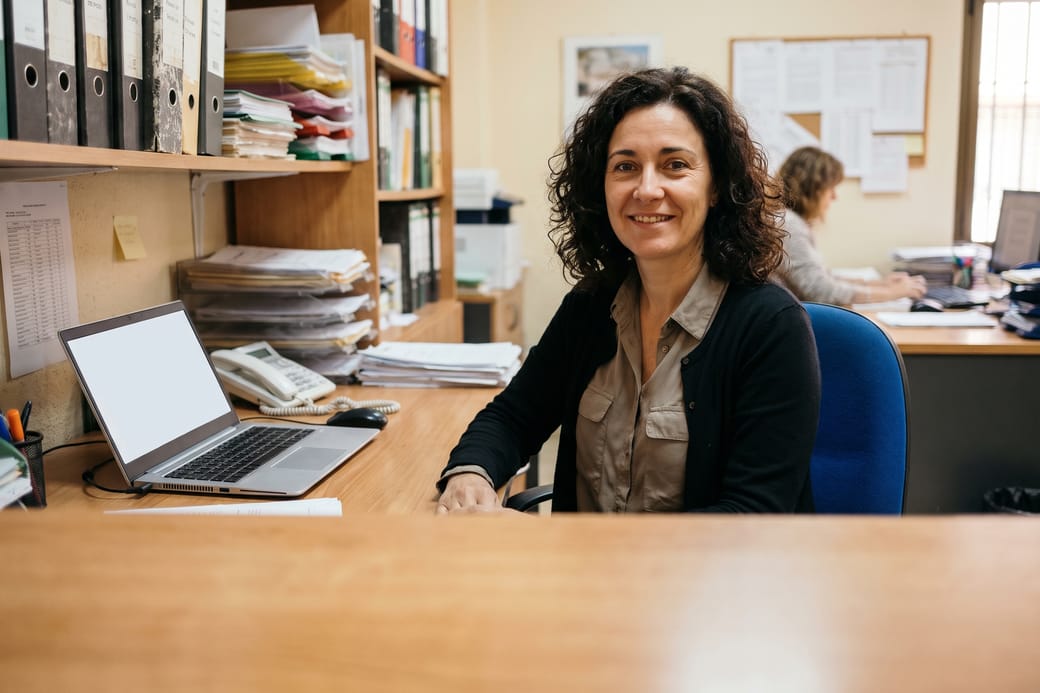 Administradora de fincas en su despacho, rodeada de archivadores